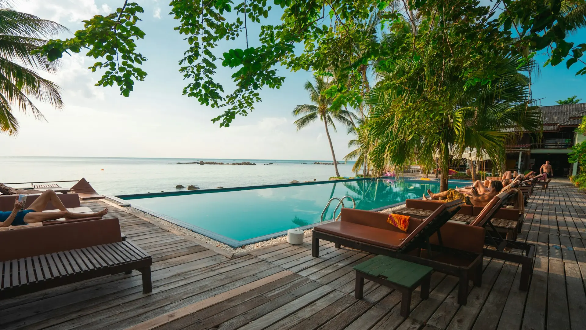 Hospitality Odoo solutions brown wooden table and chairs on brown wooden deck near body of water during daytime